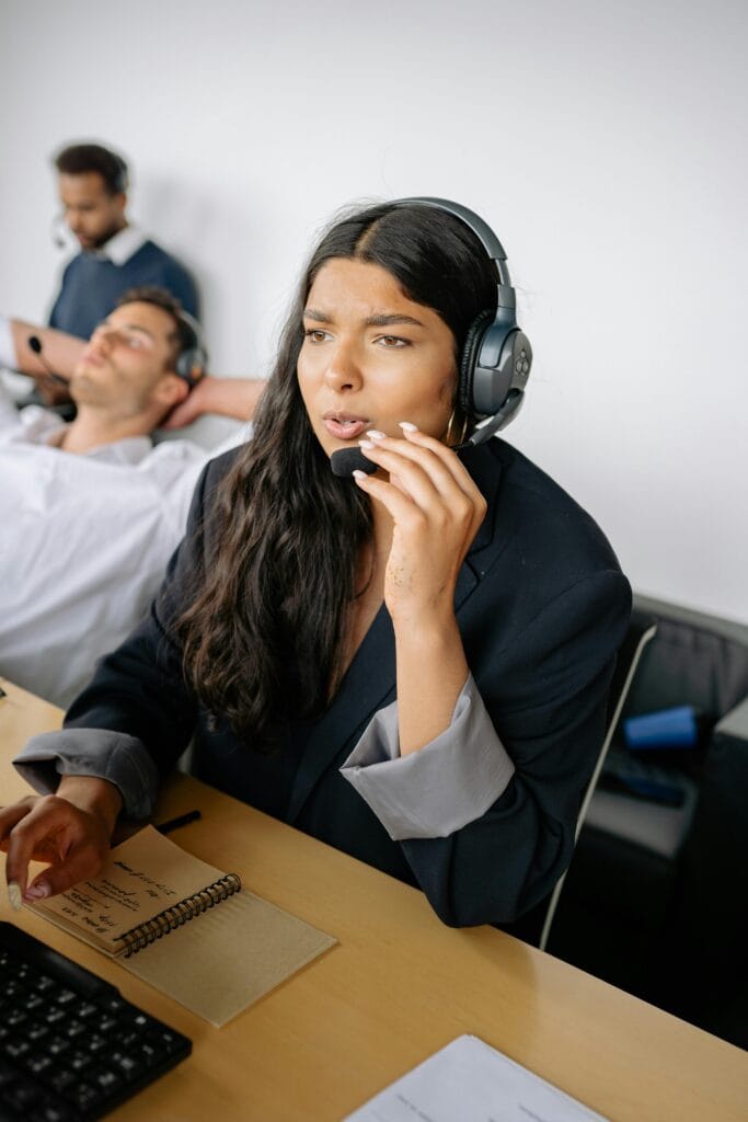 A professional woman using a headset and working in a call center environment.
